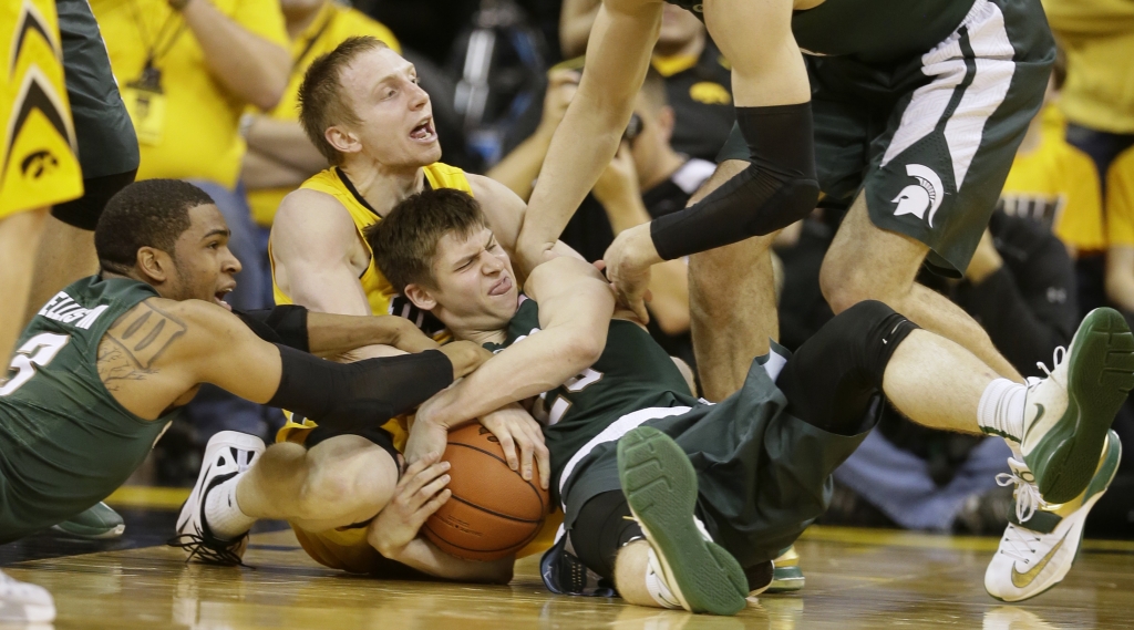 Iowa guard Mike Gesell center fights for the ball with Michigan State's Alvin Ellis III left and Matt McQuaid right during the first half of an NCAA college basketball game Tuesday Dec. 29 2015 in Iowa City Iowa. (AP