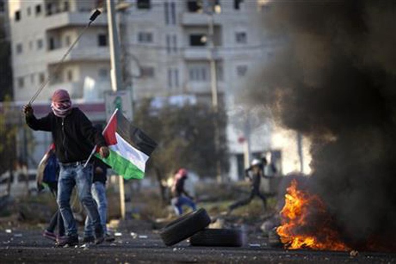 Palestinian protesters throw stones at Israeli troops during clashes following a demonstration to demand the release of bodies of Palestinian attackers being held by Israeli authorities in the West Bank city of Ramallah Sunday Nov. 29 2015