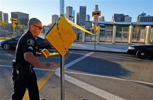 A police officer puts up yellow tape to close the school outside of Edward Roybal High School in Los Angeles on Tuesday morning Dec. 15 2015. All schools in the vast Los Angeles Unified School District the nation's second largest have been order