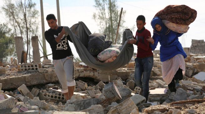 Syrians collect items from their destroyed house in the Al Shallal suburb of the northeastern town of Al Hol in Syria's Hasakeh province bordering with Iraq