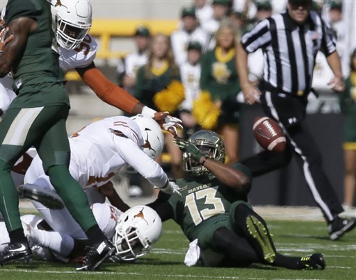 Baylor quarterback Chris Johnson fumbles the ball under pressure from Texas defenders Charles Omenihu and Bryce Cottrell during the first half of an NCAA college football game Saturday Dec. 5 2015 in Waco Texas