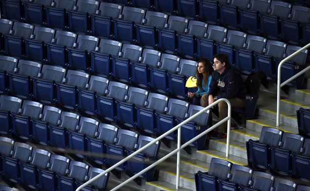 A few fans are surrounded by empty seats in a section of the stadium as the St. Louis Rams play the Tampa Bay Buccaneers during the third quarter of an NFL