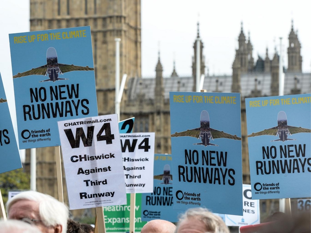 Protesters hold signs during a rally against a third runway at Heathrow airport in Parliament Square