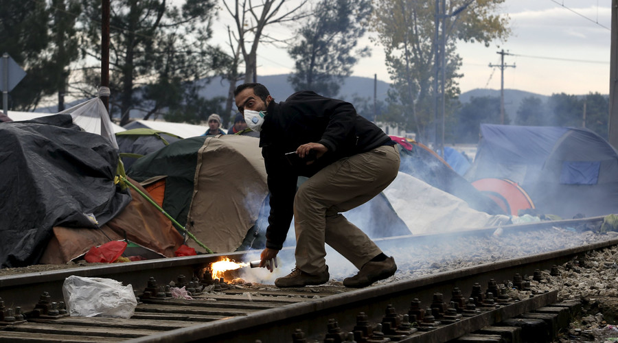 A stranded migrant throws a tear gas canister back to Macedonian police officers as minor clashes broke out during a protest against the building of a metal fence at the Greek Macedonian borders near the village of Idomeni Greece