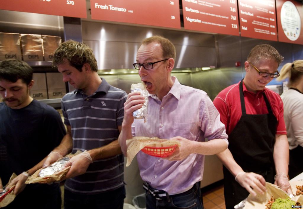 FILE- Steve Ells center CEO of Chipotle Mexican Grill eats a burrito at a New York Chipotle restaurant. The chain's loaded chicken burrito contains 2,790 mg of sodium