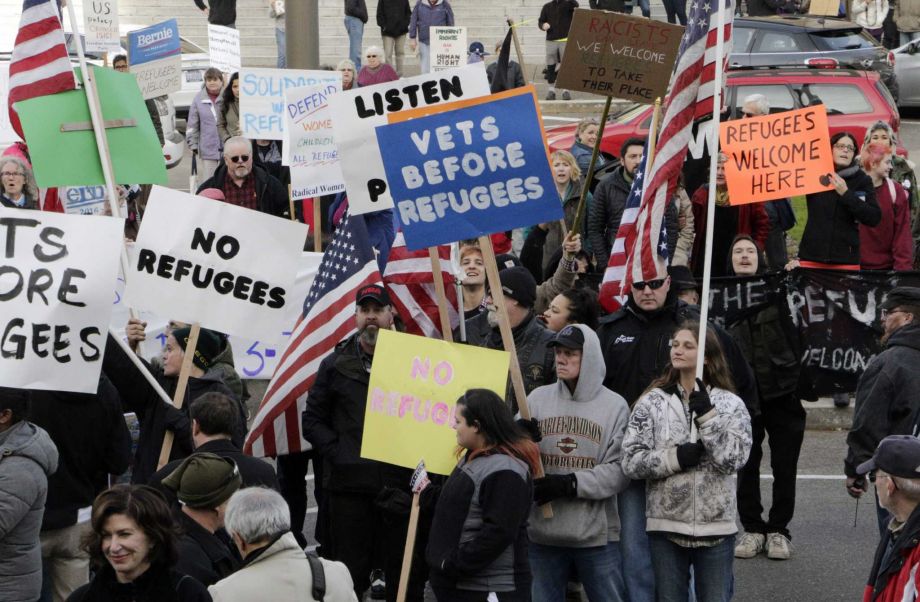 Protesters on opposing sides of the Syrian refugee resettlement issue rally in front of the state Capitol in Olympia Wash. Friday Nov. 20 2015. Washington Gov. Jay Inslee has said the state will welcome refugees and has criticized other governors who