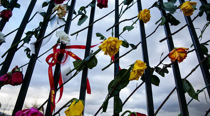 Roses are placed on the fence at a make shift memorial for those killed and injured setup near the Inland Regional Center