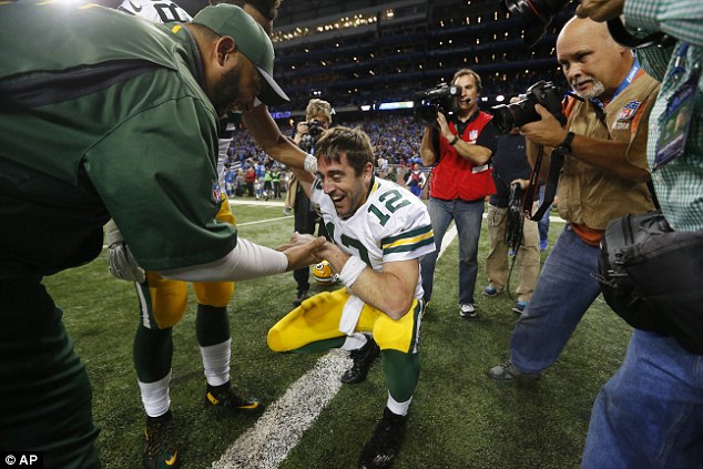 Pakcers quarterback Rogers sinks to the floor and is congratulated after winning the game for his team