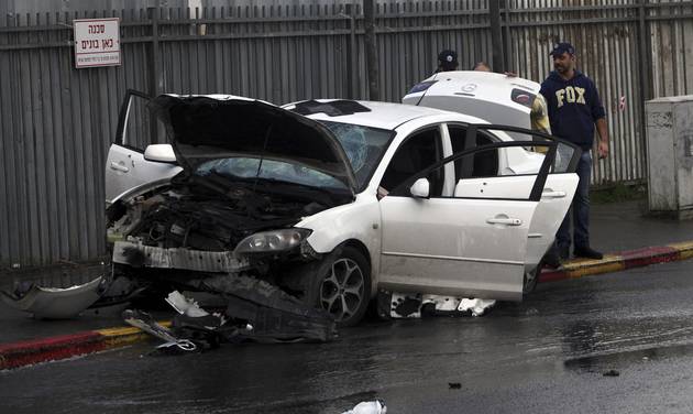 Israeli police examine a car used in a vehicular attack in Jerusalem Monday Dec. 14 2015. A Palestinian rammed his car into a bus station wounding nine people before he was shot and killed by bystanders police said