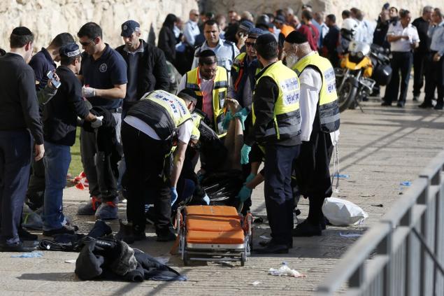 Volunteers wrap in a plastic bag the body of a Palestinian assailant who was shot dead following a reported stabbing attack next to Jerusalem's Old City