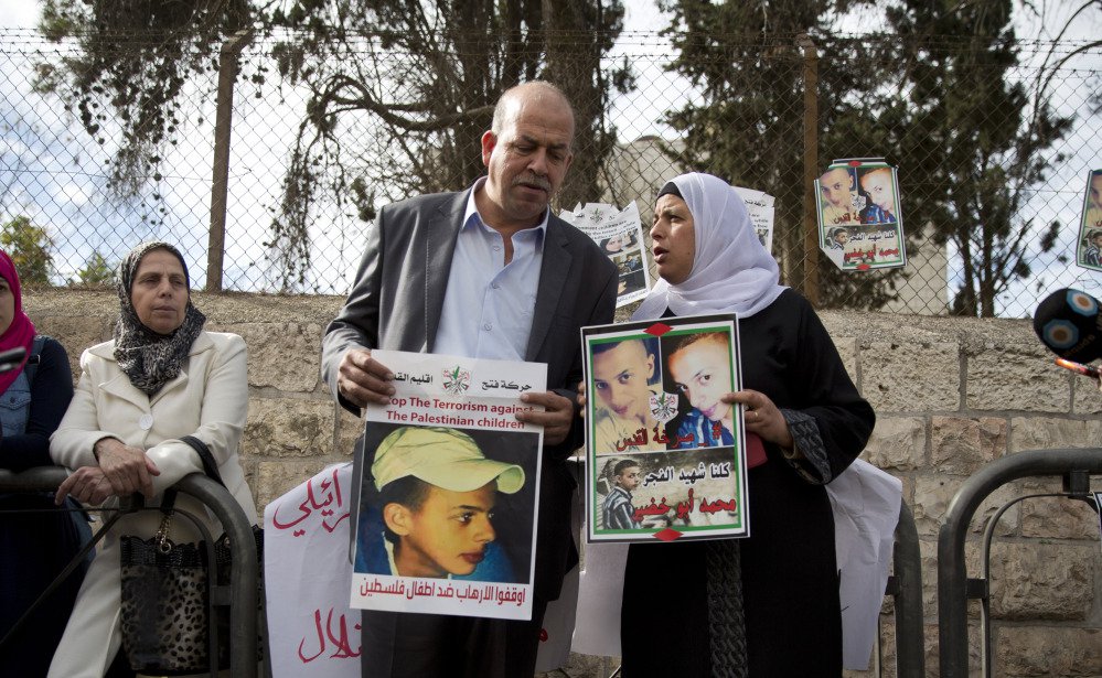 Suha and Hussein Abu Khdeir center parents of Mohammed Abu Khdeir hold posters with his portrait after the reading of the verdict in his killing Monday at Jerusalem District Court. The court convicted two Israeli youths in the grisly murder of Abu Khde