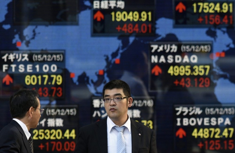 Pedestrians stand in front of a stock markets indicator board in Tokyo. Shares in Tokyo rose strongly after two days of losses. /EPA