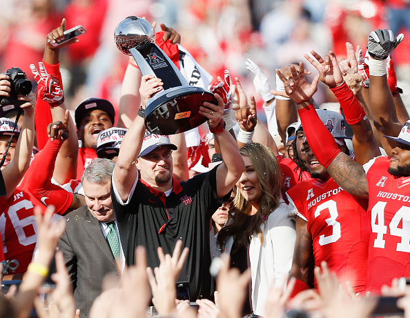 HOUSTON TX- DECEMBER 05 Head coach Tom Herman of the Houston Cougars raises the AAC Championship Trophy at TDECU Stadium