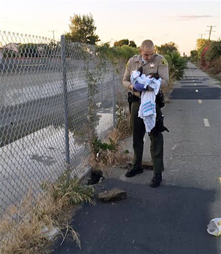 Los Angeles County Sheriff's Department shows Deputy Adam Collette holding an infant girl where she was found abandoned under asphalt and rubble near a bike path in Compton Calif. as the