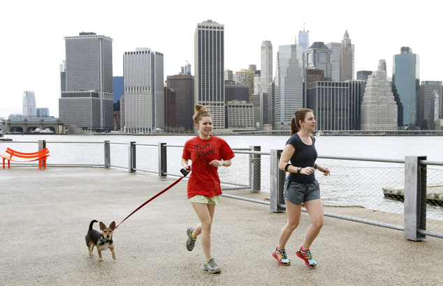 Joggers dressed in shorts and T-shirts run in Brooklyn Bridge Park in New York as the Lower Manhattan skyline is seen behind them Thursday Dec. 24 2015