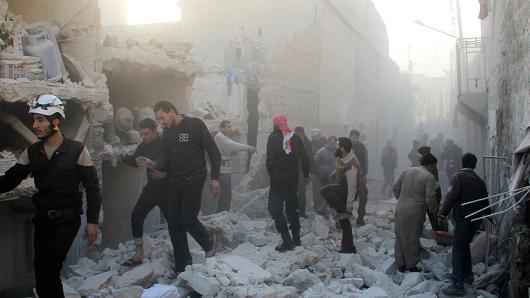 Syrians walk on debris of collapsed buildings after the war-crafts belonging to the Russian army carried out airstrikes on the opposition-controlled neighborhoods in Aleppo Syria