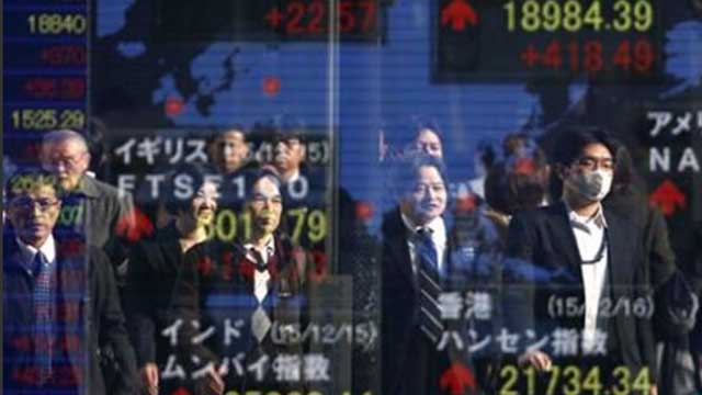 People are reflected on an electronic stock board along with global stock indexes at a securities firm in Tokyo Wednesday Dec. 16 2015. Asian stocks posted strong gains Wednesday ahead of a widely expected decision by the Fed to raise interest rates fro