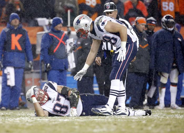 New England Patriots tight end Rob Gronkowski lies injured on the field against the Denver Broncos as teammate tight end Scott Chandler trees to help him up during the second half of an NFL football game Sunday Nov. 29 2015 in Denver. (AP Ph