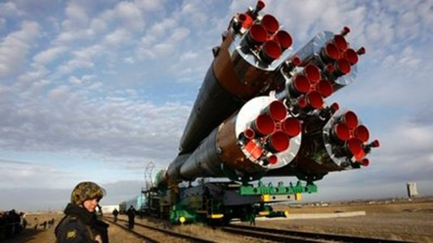 A Russian police officer guards the Russian Soyuz TMA-18 space ship getting transported from a hangar to the launch pad at the Russian leased Baikonur Cosmodrome Kazakhstan