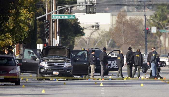 Investigators gather around a Black SUV that was involved in Wednesday's police shootout with suspects in San Bernardino CA