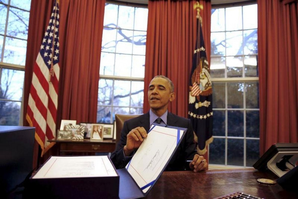 US President Barack Obama reacts as after signing the $1.1 Trillion Government Funding Bill into Law at the Oval Office of the White House in Washington