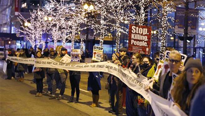 Protesters march through Chicago's Loop carrying what organizers say is a banner of names of people tortured and in prison as they also call for Chicago Mayor Rahm Emanuel and Cook County State's Attorney Anita Alvarez to resign in the wake