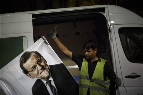 A worker removes a campaign poster for the national elections depicting Spain's Prime Minister and Popular Party candidate Mariano Rajoy in Madrid Spain Monday Dec. 21 2015. A strong showing Sunday by a pair of upstart parties in Spain's general elec