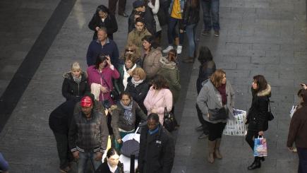 People queue along a street in Madrid to buy lottery tickets