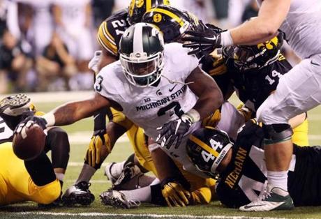 Despite being wrapped up by a gang of Iowa defenders Michigan State’s L.J. Scott stuck the ball over the goal line for the winning touchdown