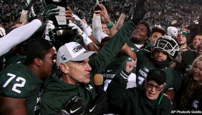 Michigan State coach Mark Dantonio left university president Lou Anna Simon bottom right and players celebrate with their Big Ten East Division Championship trophy after beating Penn State 55-16 in an NCAA college football game Saturday Nov. 28 201