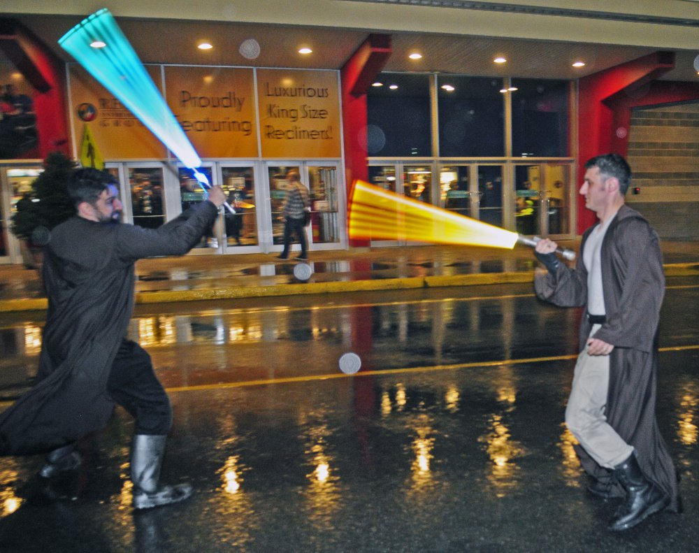 Peter Spiegel left and Brian Juengst have a light saber battle in the parking lot Thursday at Regal Cinema in Augusta. The men were returning their brightly lighted plastic toys to their car since no replica weapons or masks are allowed in the theaters