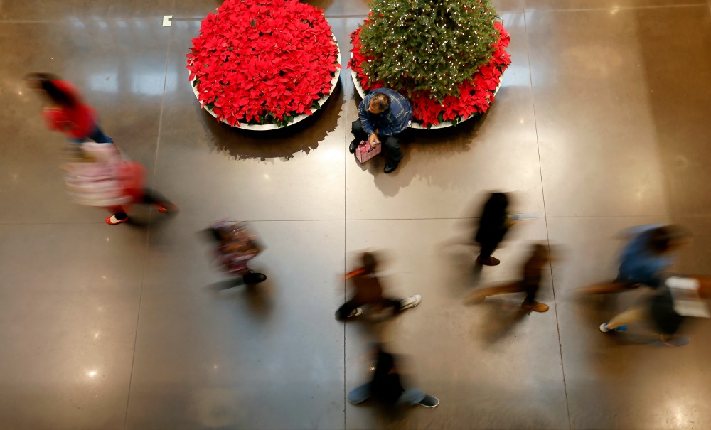 Shopper Eruain Nieto sits on the edge of a plant pot while waiting for his daughter who shops at the H&M store at North Park Center in Dallas on Black Friday