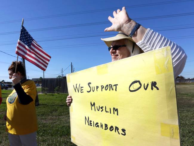 Jane Malin holds a sign as she waves to passing cars during a rally to show support for Muslim members of the community near the Clear Lake Islamic Center in Webster Texas on Friday Dec. 4 2015