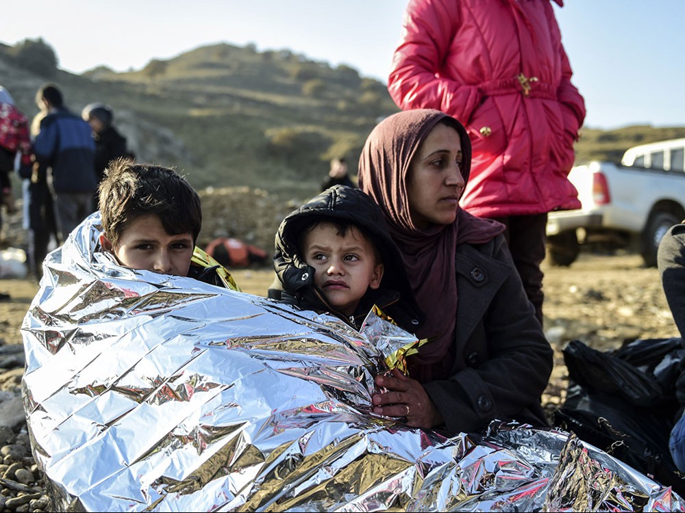 A Syrian family waits after arriving on the Greek island of Lesbos along with other migrants and refugees