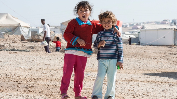 Two young Syrian refugee girls smiles for the camera in the Zaatari Refugee Camp near the city of Mafraq Jordan on Sunday Nov. 29 2015