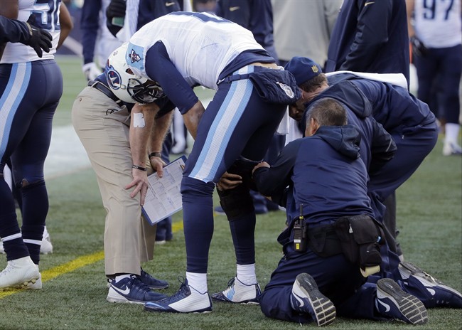 Tennessee Titans quarterback Marcus Mariota has a knee brace fitted on the sideline in the first half of an NFL football game against the New England Patriots Sunday Dec. 20 2015 in Foxborough Mass. Mariota did not return to the game. (AP