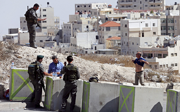 A Palestinian man pulls up his shirt during a security check by Israeli paramilitary border policemen at a roadblock set-up by Israel this week in an effort to stop a wave of Palestinian knife attacks