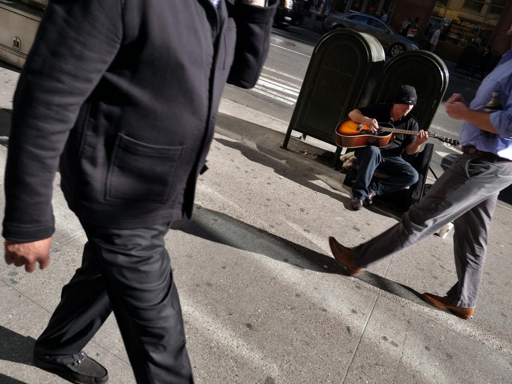 Facing the music... New Yorkers pass a busker as fears grow that the booming US economy could be severely impacted by the impending interest rate rise