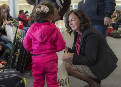 Canada's ambassador to Lebanon Michelle Cameron offers a teddy bear to a Syrian child at the beginning of an airlift of Syrian refugees to Canada at the Beirut International airport