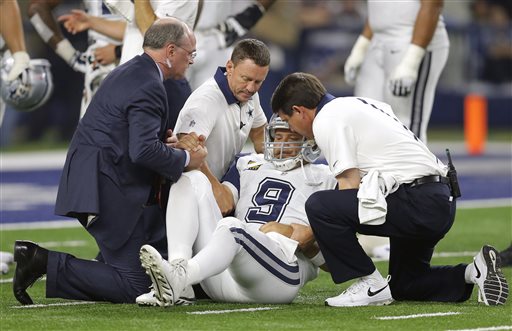 Dallas Cowboys quarterback Tony Romo is helped off the field by team staff after suffering an unknown injury in the second half of a game against the Carolina Panthers Nov. 26 2015 in Arlington Texas