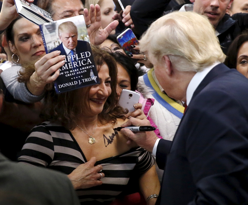 Republican presidential candidate Donald Trump autographs the chest of a woman at his campaign rally in Manassas Virginia