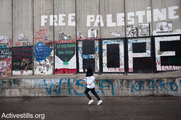 A young woman runs next to the Israeli separation wall as hundreds of Palestinian and international athletes took part in the the inaugural Palestine Marathon which took place in Bethlehem West Bank