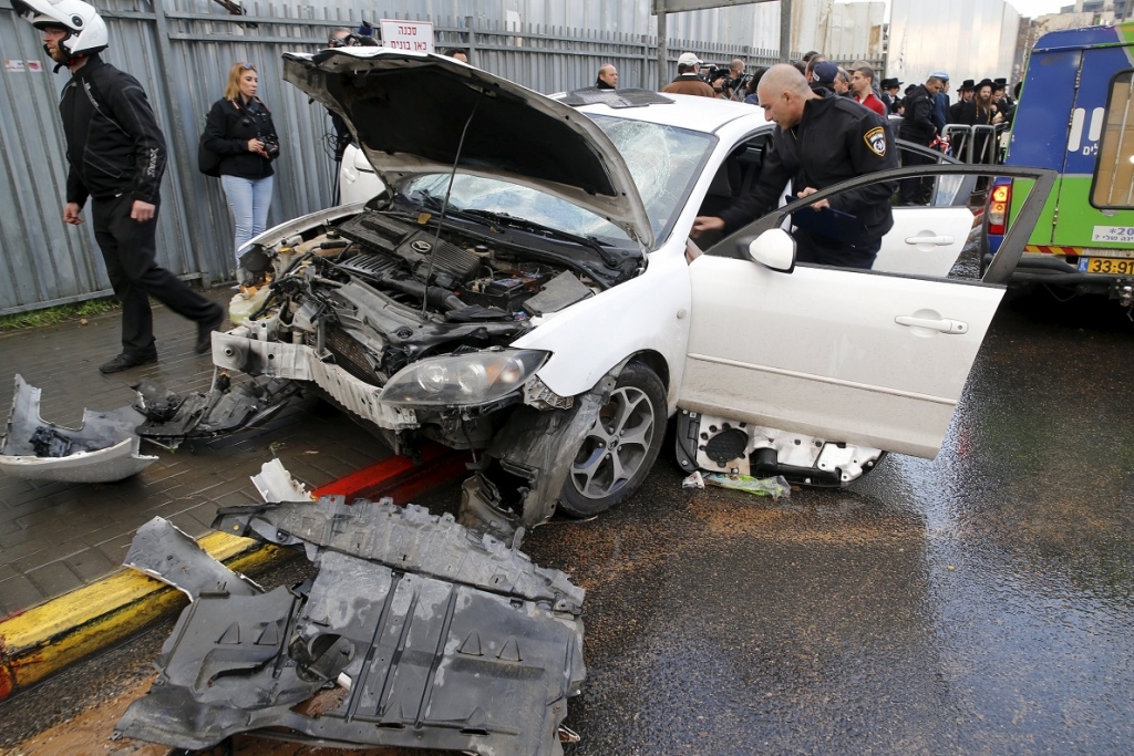 An Israeli policeman checks a car at the scene where a motorist rammed into a bus stop injuring at least nine people before he was shot dead in Jerusalem. – Reuters pic