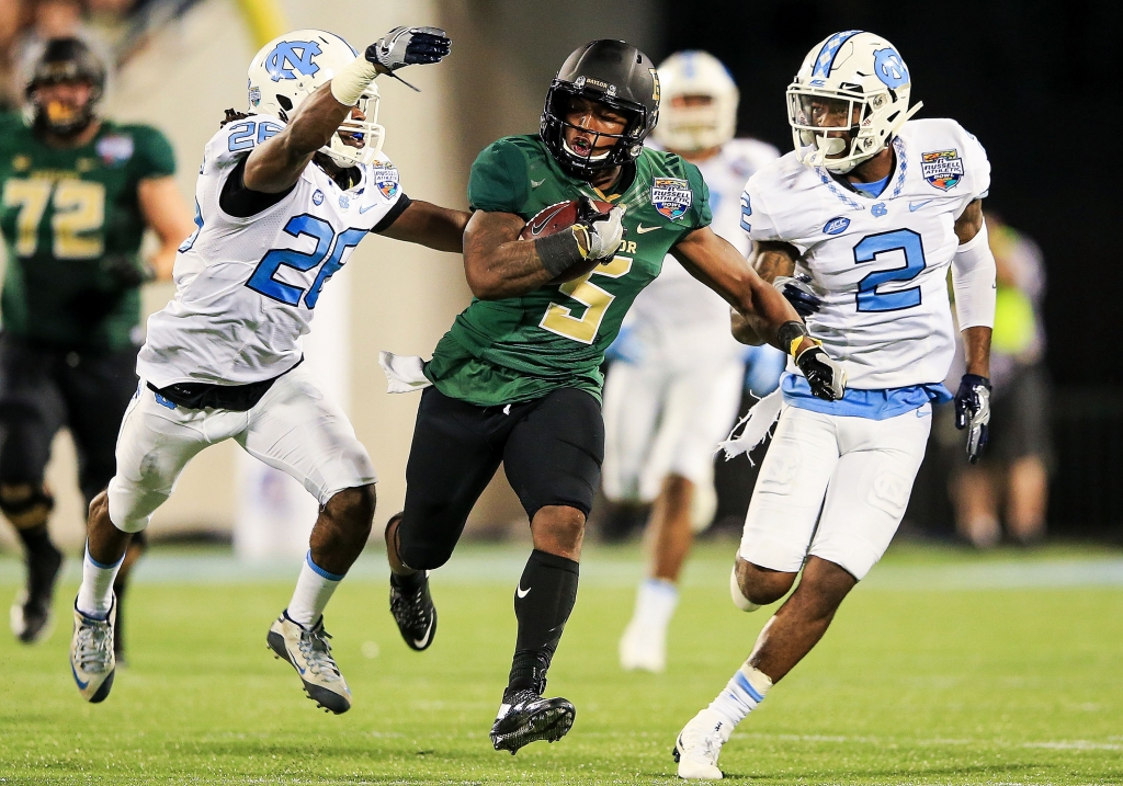 ORLANDO FL- DECEMBER 29 Johnny Jefferson #5 of the Baylor Bears carries while defended by Dominquie Green #26 and Des Lawrence #2 of the North Carolina Tar Heels during the first half of the Russell Athletic Bowl game at Orlando Citrus Bowl on December