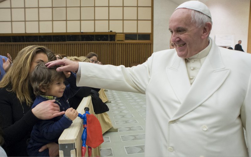 Pope Francis blesses a child during a special audience with Vatican employees for Christmas greetings at the Paul VI hall at the Vatican