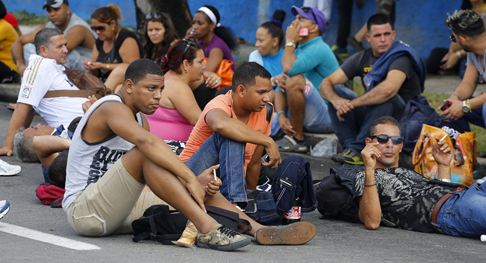 Cubans interrupt traffic sitting on a portion of Fifth Avenue near Ecuador's embassy to express discontent with a new visa rule that now requires Cubans have a visa to visit the South American country in Havana Cuba Saturday Nov. 28 2015