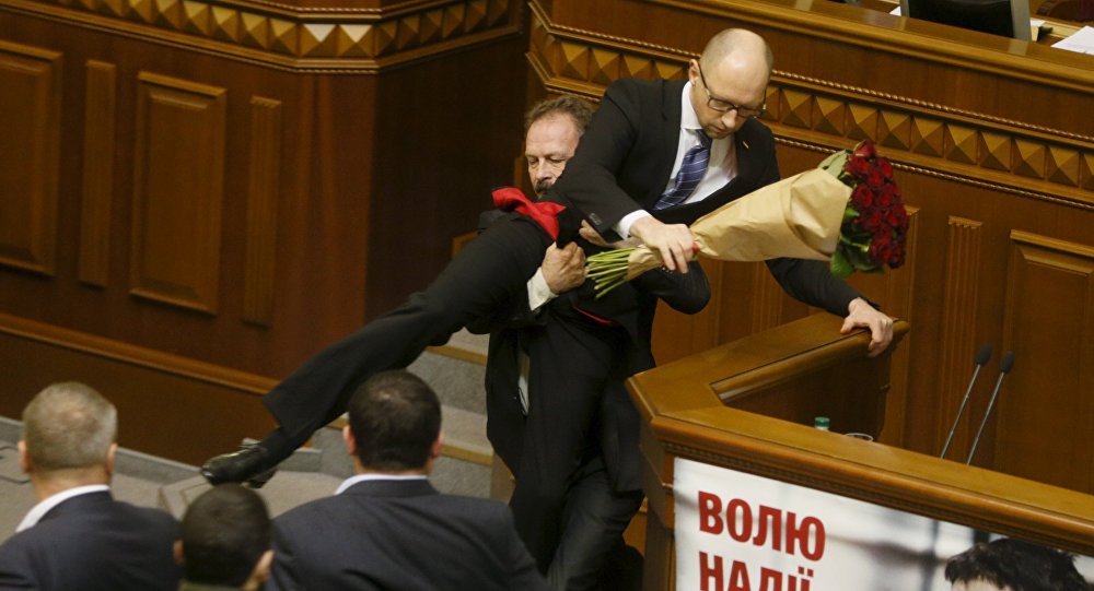 Rada deputy Oleg Barna removes Prime Minister Arseny Yatseniuk from the tribune after presenting him a bouquet of roses during the parliament session in Kiev Ukraine