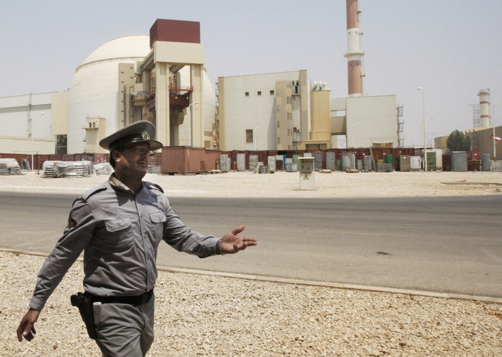 An Iranian security officer directs media at the Bushehr nuclear power plant with the reactor building seen in the background just outside the southern city of Bushehr Iran