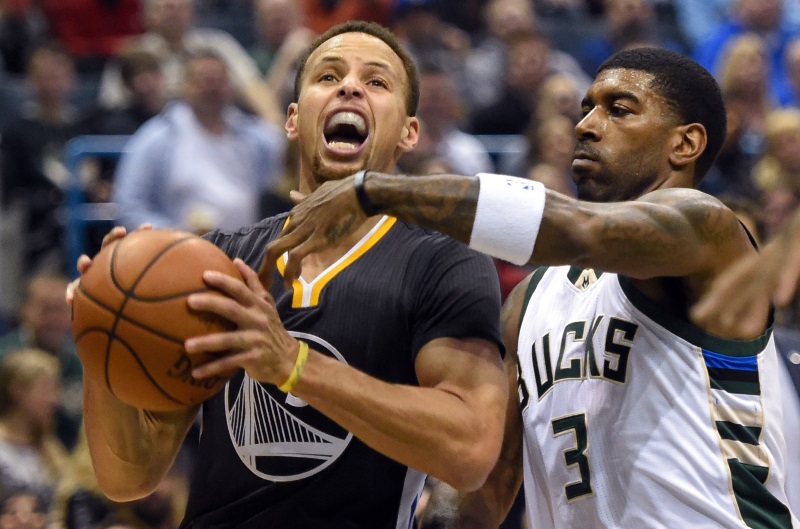 Warriors guard Steph Curry drives to the hoop as Bucks guard OJ Mayo reaches for the ball