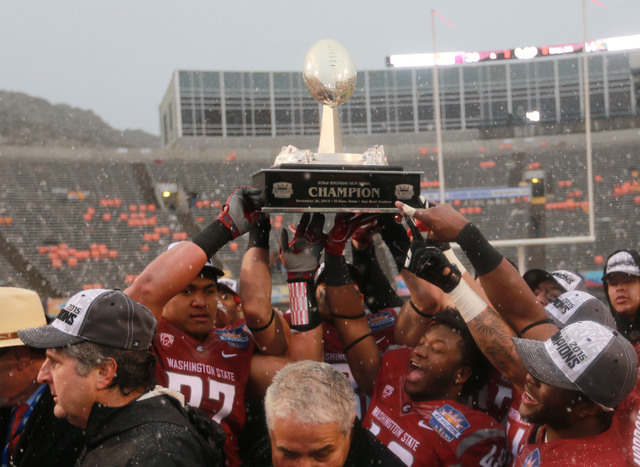 ASSOCIATED PRESS           Washington State players hoist the Sun Bowl NCAA college football game trophy after defeating Miami 20-14 today in El Paso Texas. Washington State head coach Mike Leach lower left looks